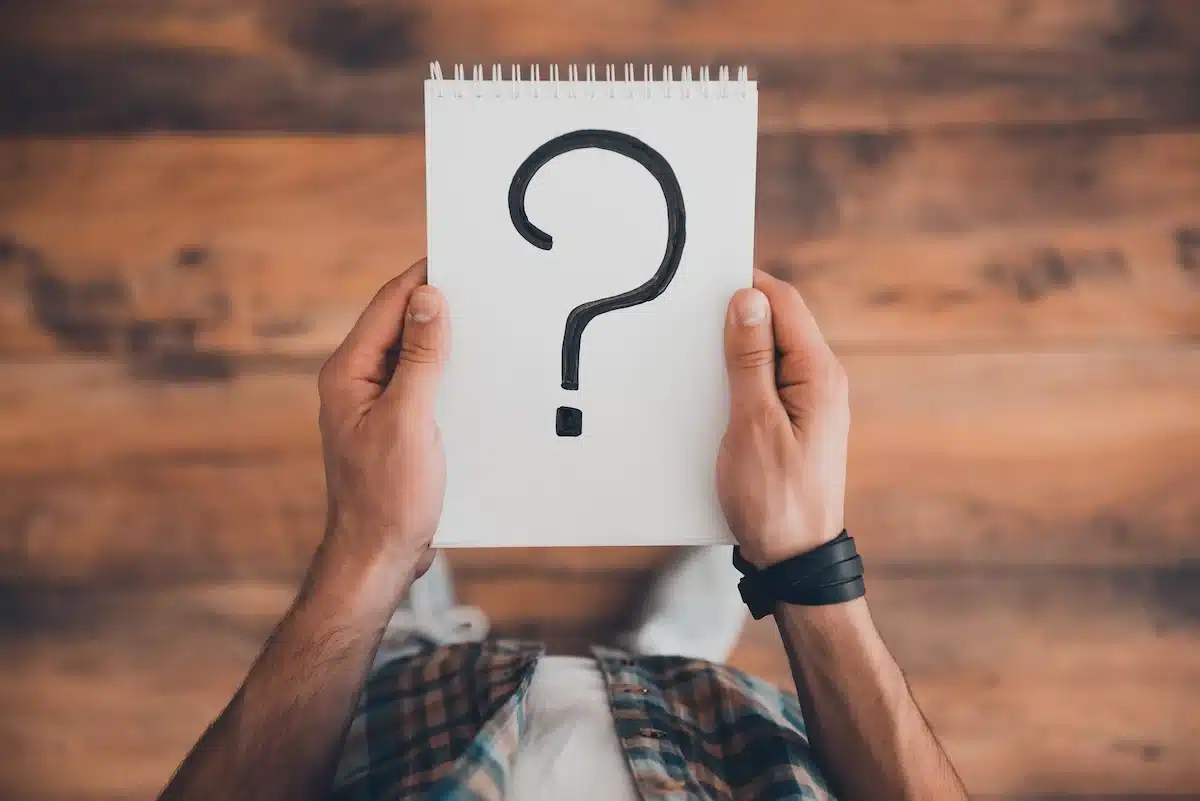 man holding a blank page with a question mark on it.